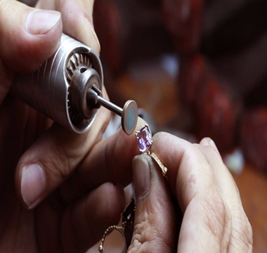 Golden ring with a purple stone being resized. Two hands show doing the work.